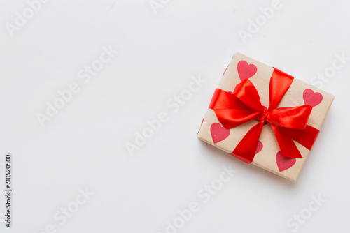 Top view photo of valentine day decorations gift box with red ribbon bow on colored background. Holiday gift boxes with top view © sosiukin