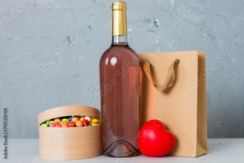 Bottle of wine on colored background for Valentine Day with gift box. Heart shaped with presrnt box perspective view with copy space photo