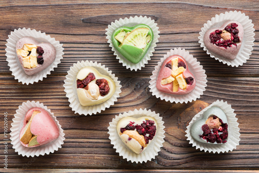 chocolate sweets in the form of a heart with fruits and nuts on a colored background. top view with space for text, holiday concept chocolate sweets in the form of a heart with fruits and nuts on a colored background. top view with space for text, holiday concept