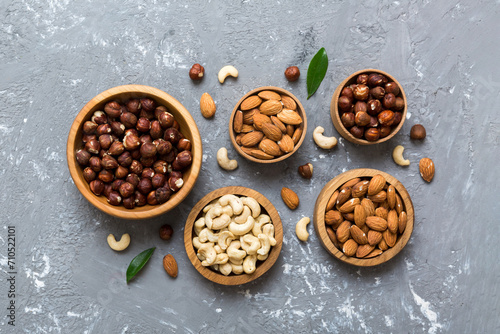 Assortment of nuts in wooden bowl on colored table. Cashew, hazelnuts, walnuts, almonds. Mix of nuts Top view with copy space