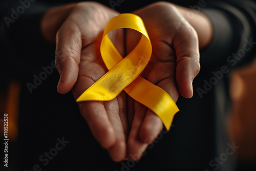 person holding yellow awareness ribbon photo
