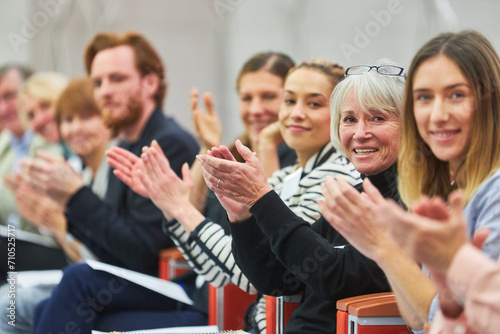 Smiling professionals clapping at business conference in auditorium photo