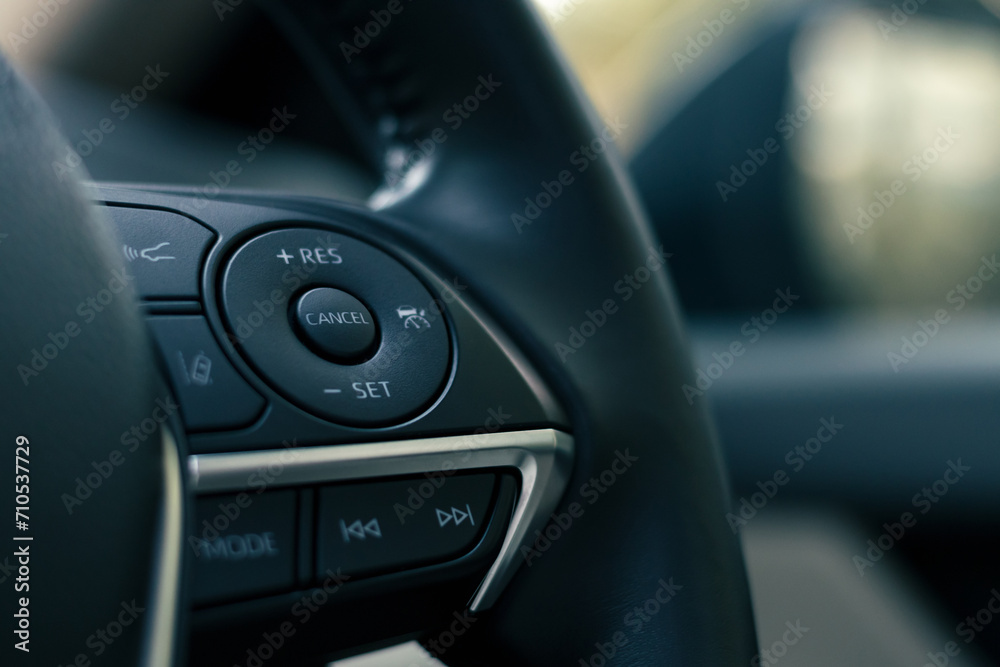 steering wheel buttons for cruise control functions, automatic speed limiter in modern car, shallow depth of field