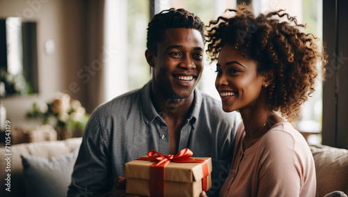 St. Valentine's Day. Young African American couple smiling on their special day, giving each other gifts. Exchange of gifts between a girl and a guy. Romance, tenderness and joy of love. Lovers photo