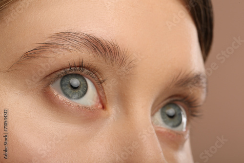 Fototapeta Naklejka Na Ścianę i Meble -  Woman with beautiful natural eyelashes on light brown background, closeup
