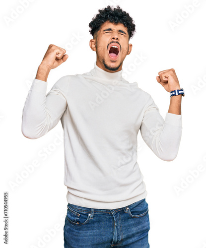 Young arab man wearing casual winter sweater angry and mad screaming frustrated and furious, shouting with anger. rage and aggressive concept.
