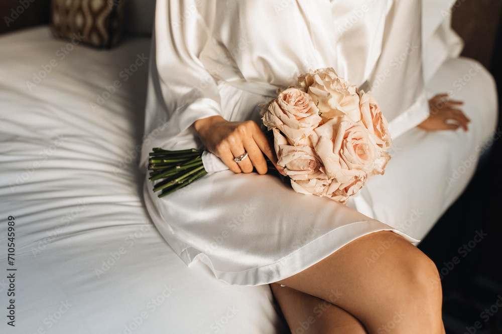 Obraz premium A close-up photo of the bride's luxurious bouquet in her hands with a wedding ring. The girl holds a bouquet of roses before the wedding