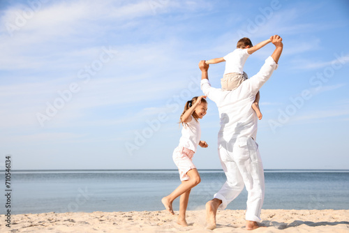 Cute little children with grandfather spending time together on sea beach