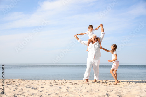 Cute little children with grandfather spending time together on sea beach