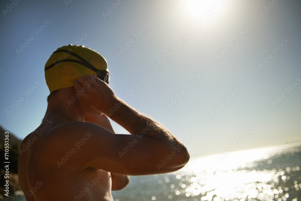 Sea, beach sunset and man for swimmer exercise, workout or outdoor training in ocean, nature or water. Mockup space, swimming cap and athlete ready to start challenge, fitness competition or cardio