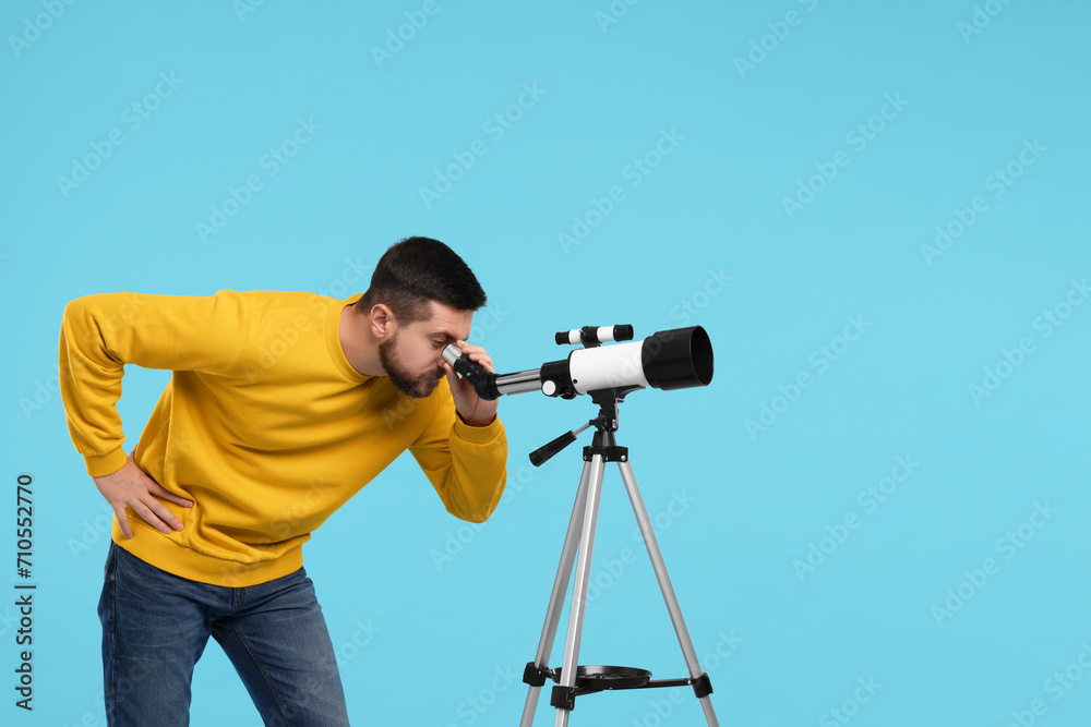 Astronomer looking at stars through telescope on light blue background. Space for text
