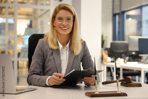 Portrait of smiling lawyer with clipboard working at table in office