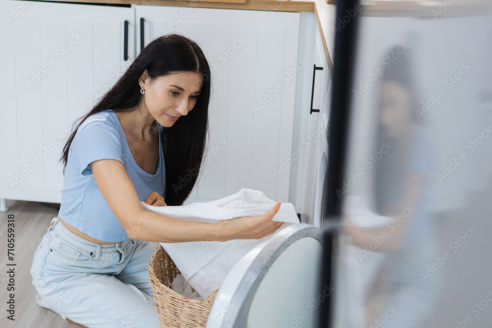Laundry and housework concept. woman who is a housewife doing laundry on vacation. Female is putting clothes into washing machine. Laundry and housework concept. woman who is a housewife doing laundry on vacation. Female is putting clothes into washing machine.
