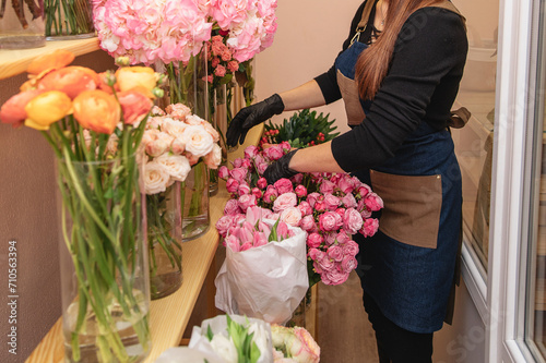 Female florist preparing boquet of roses in the shop. Close up girl creating the compose of flowers