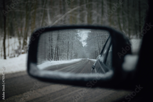 Reflection of a snowy road in a car mirror.