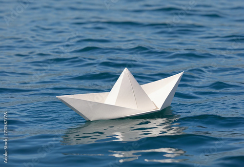 White paper boat drifting in the blue ocean