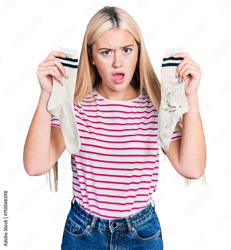 Beautiful blonde woman holding socks in shock face, looking skeptical and sarcastic, surprised with open mouth Beautiful blonde woman holding socks in shock face, looking skeptical and sarcastic, surprised with open mouth