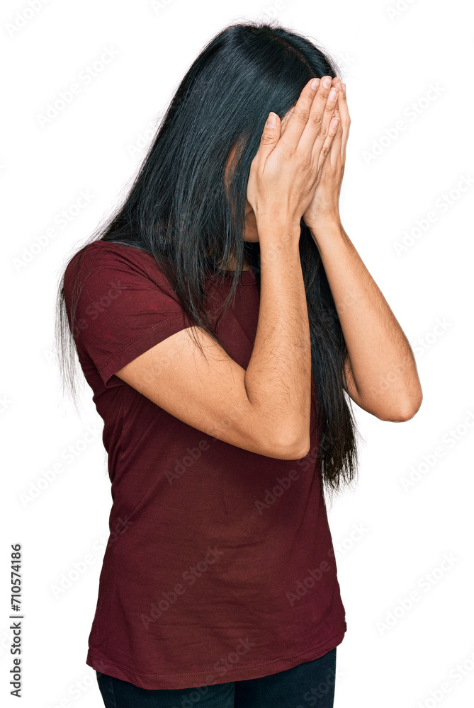 Young hispanic girl wearing casual t shirt with sad expression covering face with hands while crying. depression concept.
