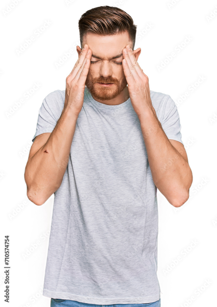 Young redhead man wearing casual grey t shirt with hand on head for pain in head because stress. suffering migraine. Young redhead man wearing casual grey t shirt with hand on head for pain in head because stress. suffering migraine.