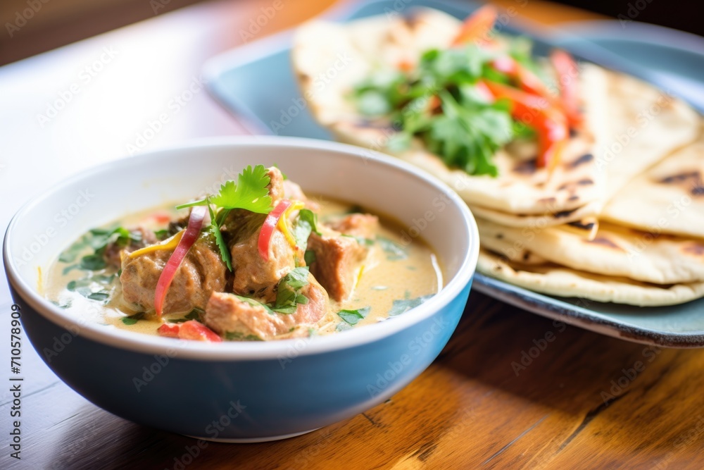 lamb korma in a ceramic dish, yogurt dollop, with naan on the side lamb korma in a ceramic dish, yogurt dollop, with naan on the side