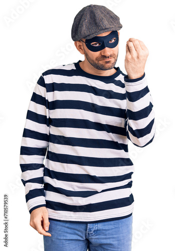 Young handsome man wearing burglar mask doing italian gesture with hand and fingers confident expression © Krakenimages.com
