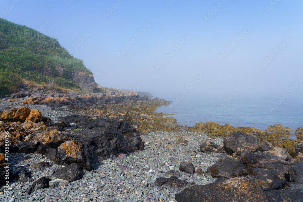 On the rocky foreshore of Porthdinllaen bay in Wales on a foggy summer afternoon.