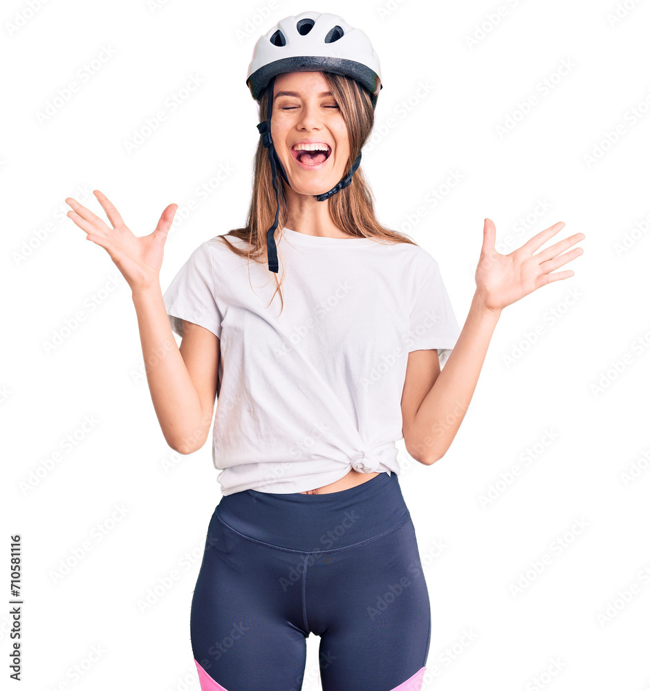 Young beautiful girl wearing bike helmet celebrating mad and crazy for success with arms raised and closed eyes screaming excited. winner concept Young beautiful girl wearing bike helmet celebrating mad and crazy for success with arms raised and closed eyes screaming excited. winner concept
