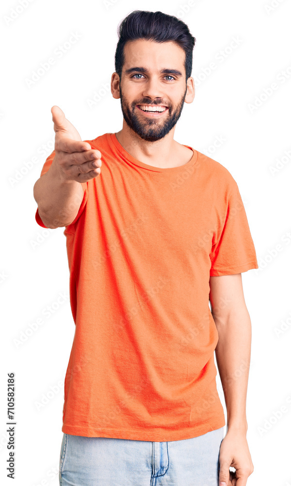 Young handsome man with beard wearing casual t-shirt smiling friendly offering handshake as greeting and welcoming. successful business. Young handsome man with beard wearing casual t-shirt smiling friendly offering handshake as greeting and welcoming. successful business.