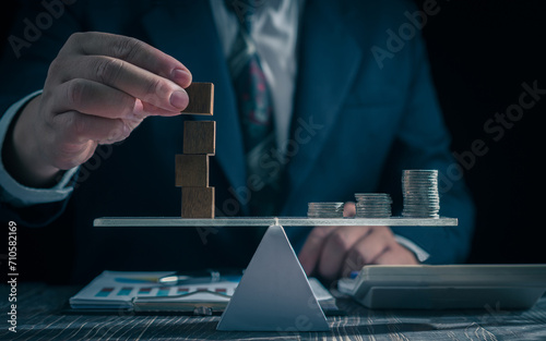 Economic risk management concept. Businessman holding wooden block . With level coin balance, banking, financial crisis, bad debt, inflation and interest rates. Investment protection.
