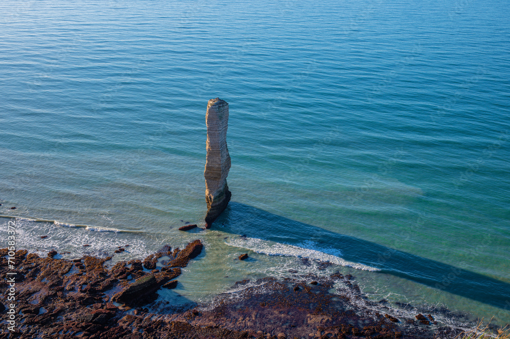 Chalk or limestone cliffs and natural arches and a pointed formation called L'Aiguille (aiguille de Belval) along the English Channel near Étretat, Normandy, France. Seascape on a clear day. Chalk or limestone cliffs and natural arches and a pointed formation called L'Aiguille (aiguille de Belval) along the English Channel near Étretat, Normandy, France. Seascape on a clear day.