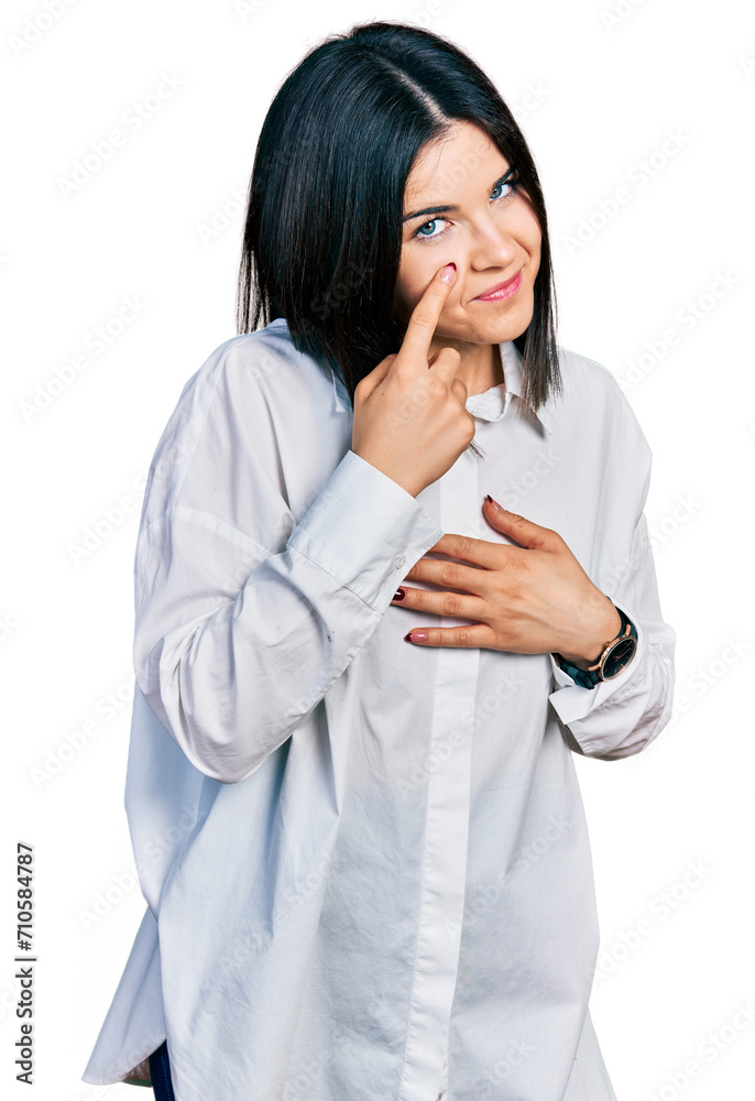 Young brunette woman with blue eyes wearing oversize white shirt pointing to the eye watching you gesture, suspicious expression Young brunette woman with blue eyes wearing oversize white shirt pointing to the eye watching you gesture, suspicious expression