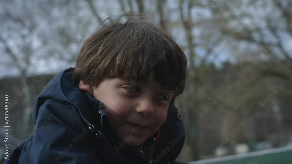 Close-up child face spinning at playground roundabout, small boy's smiling expression at outdoor park during cold fall season Close-up child face spinning at playground roundabout, small boy's smiling expression at outdoor park during cold fall season