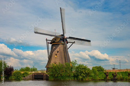 View of traditional windmills and canals in Kinderdijk Village in the Netherlands, South Holland. Famous tourist attraction in Holland. Beautiful Dutch landscape with canal and grass.