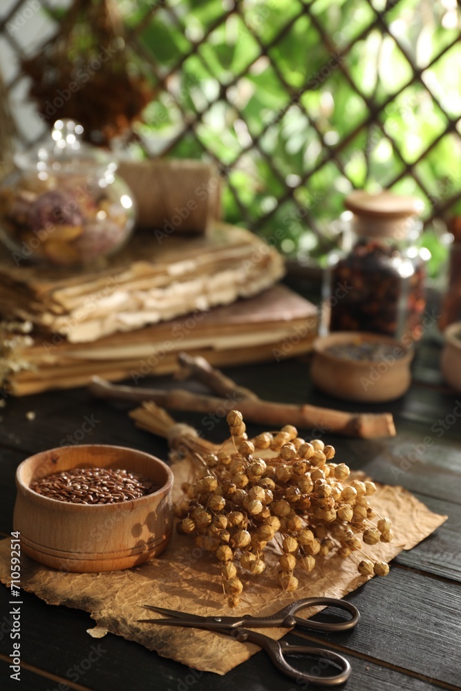 Flax seeds with dry flowers and scissors on black wooden table indoors Flax seeds with dry flowers and scissors on black wooden table indoors