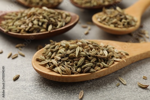 Wooden spoons with fennel seeds on grey table, closeup