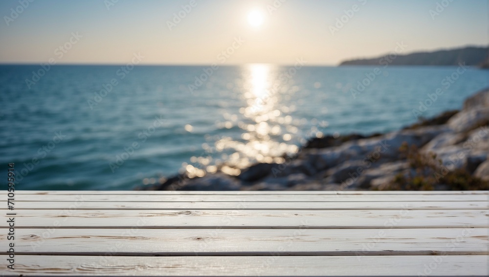 A background with an empty white wooden table and the sea or ocean. Sunset, bright sun. Spring or summer wallpaper with an empty space. Natural bokeh. Rays of light. Daylight.