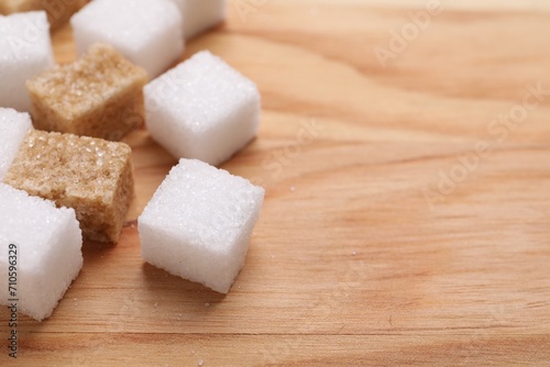 White and brown sugar cubes on wooden table, closeup. Space for text