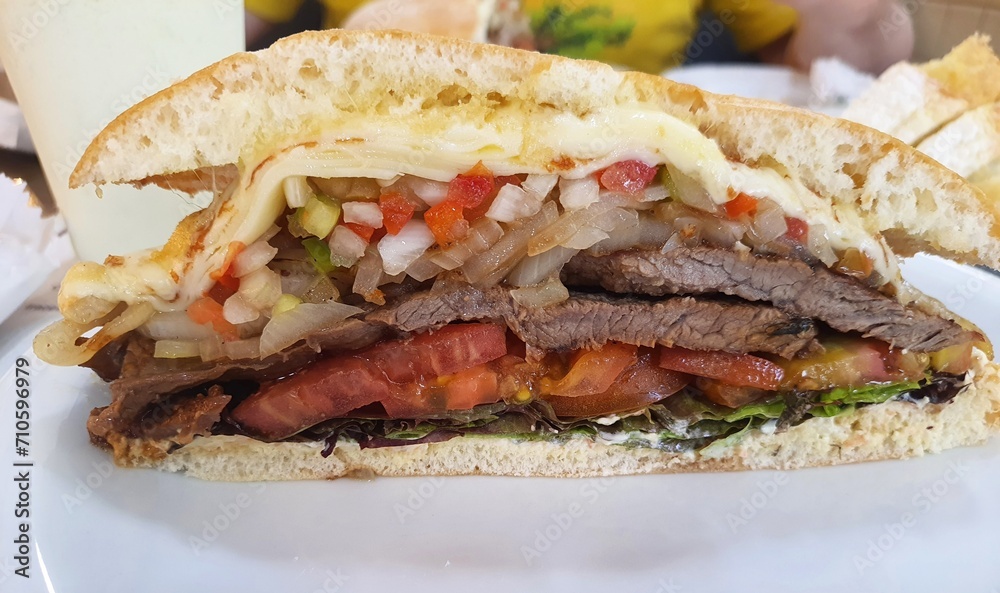 Fototapeta premium Beirut sandwich (Beirut is a Brazilian sandwich), on a plate in a restaurant, front view. The sandwich was invented in 1950 by two Lebanese brothers, owners of a coffee shop in São Paulo, Brazil.