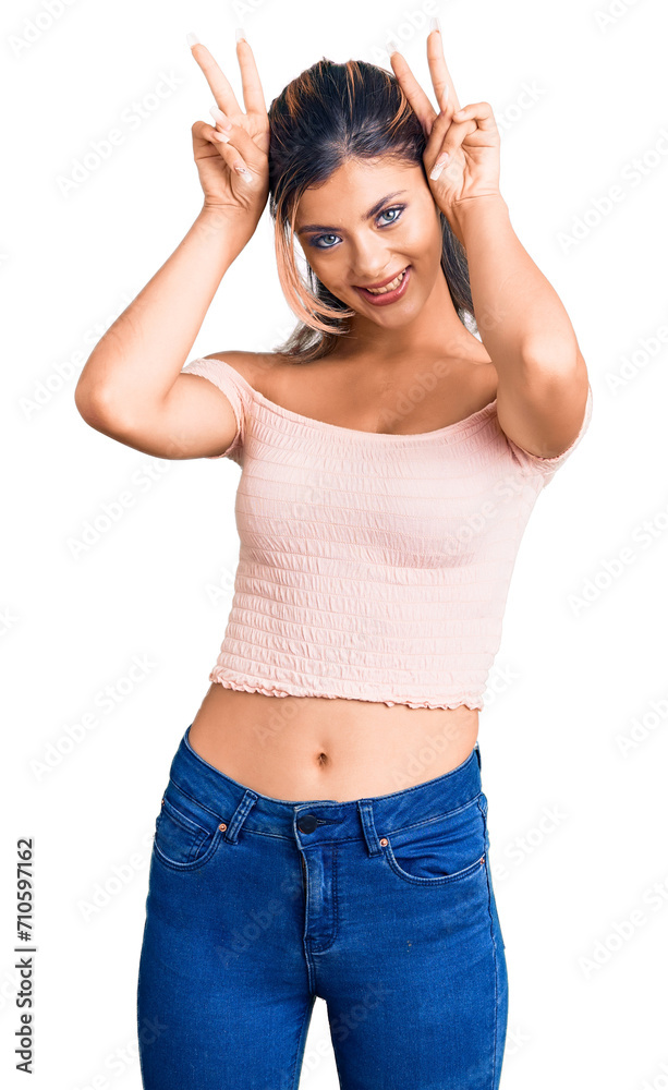 Young beautiful woman wearing casual clothes posing funny and crazy with fingers on head as bunny ears, smiling cheerful Young beautiful woman wearing casual clothes posing funny and crazy with fingers on head as bunny ears, smiling cheerful