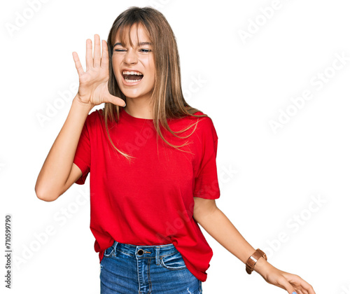 Teenager caucasian girl wearing casual red t shirt shouting and screaming loud to side with hand on mouth. communication concept.