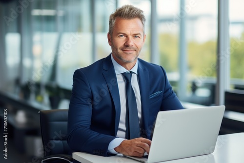 Happy busy middle aged business man ceo wearing suit sitting at desk in office using laptop. Mature businessman professional executive manager working on computer corporate technology at workplace 