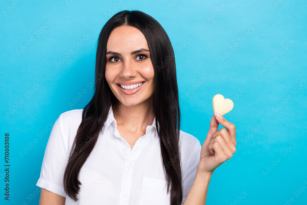 Photo of cheerful sweet girl dressed white shirt holding heart shape biscuits isolated blue color background Photo of cheerful sweet girl dressed white shirt holding heart shape biscuits isolated blue color background