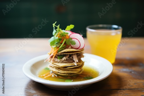 stacked birria tacos with consomme cup on the side