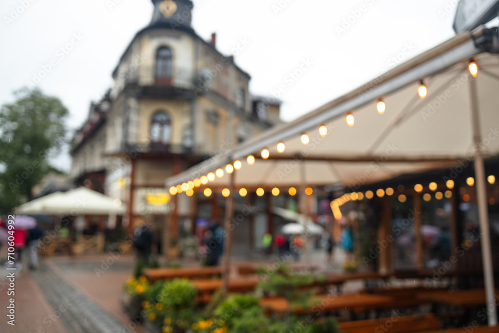 Blurred bokeh light with yellow string lights decor near city restaurant or cafe. Zakopane, Poland. Light bulbs outdoors at a party in evening time. High quality photo
