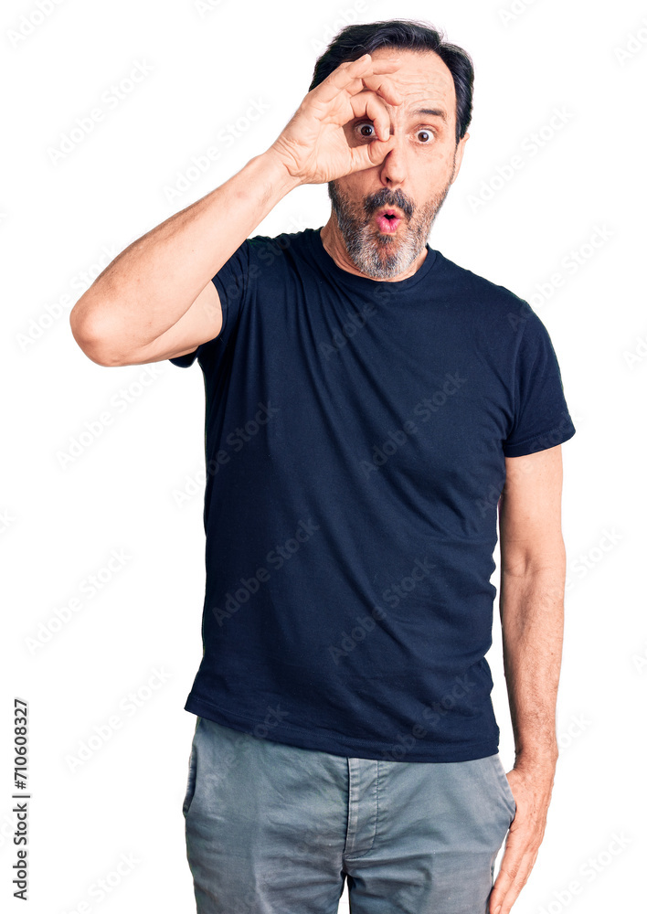 Middle age handsome man wearing casual t-shirt doing ok gesture shocked with surprised face, eye looking through fingers. unbelieving expression. Middle age handsome man wearing casual t-shirt doing ok gesture shocked with surprised face, eye looking through fingers. unbelieving expression.