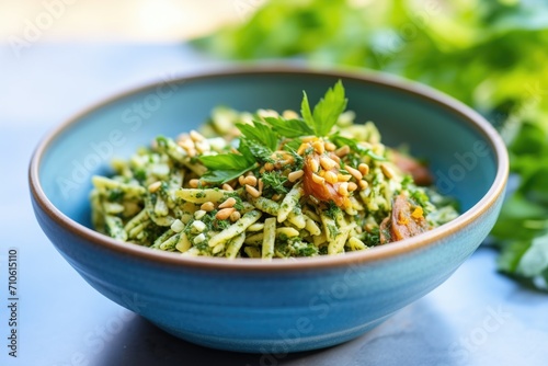 close view of spelt pasta with cashew pesto in a light blue bowl, parsley on top