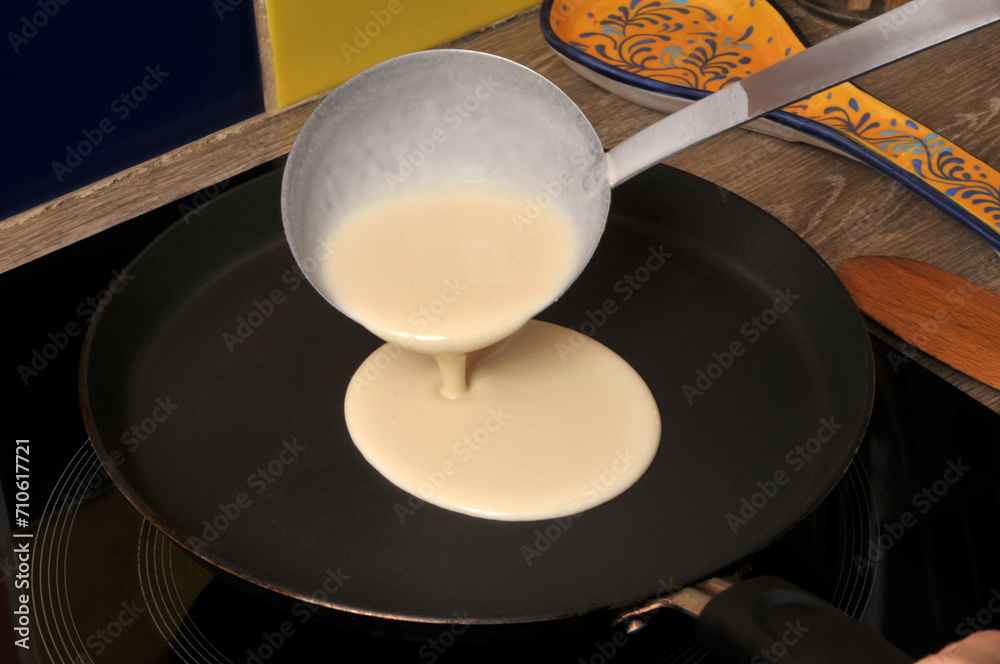 Mettre de la pâte à crêpe dans une crépière avec une louche en gros