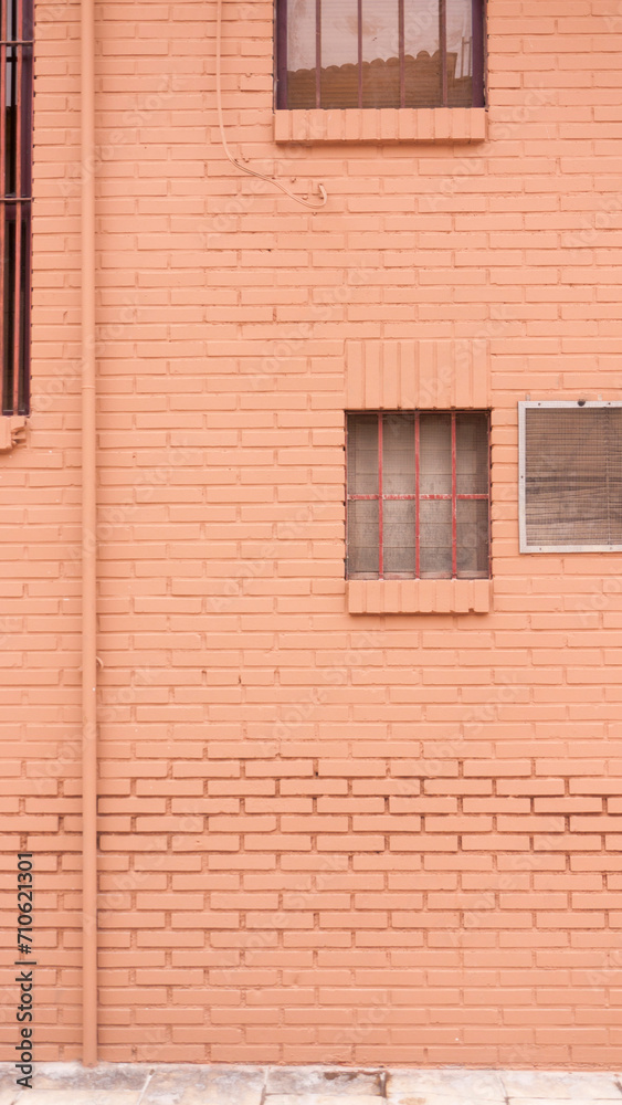 Rejilla de ventilación y ventanas en pared rosa de callejón urbano Rejilla de ventilación y ventanas en pared rosa de callejón urbano