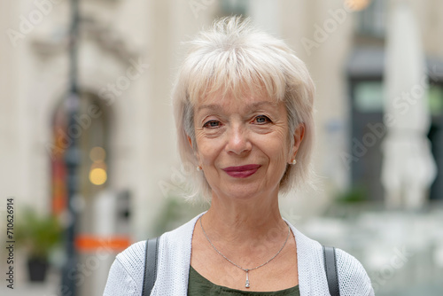фотографія Street portrait of an elderly happy woman 65-70 years old on a blurred urban background of a European street