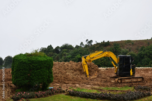 Backhoe vehicle machinery waiting dig soil thai technician fix and repair on gardening land construction site park garden of Doi Inthanon mountain with mist raining in morning in Chiang Mai, Thailand